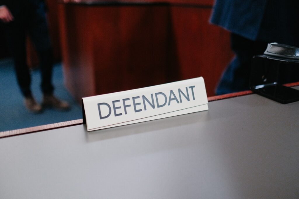 desk with a sign "DEFENDANT"