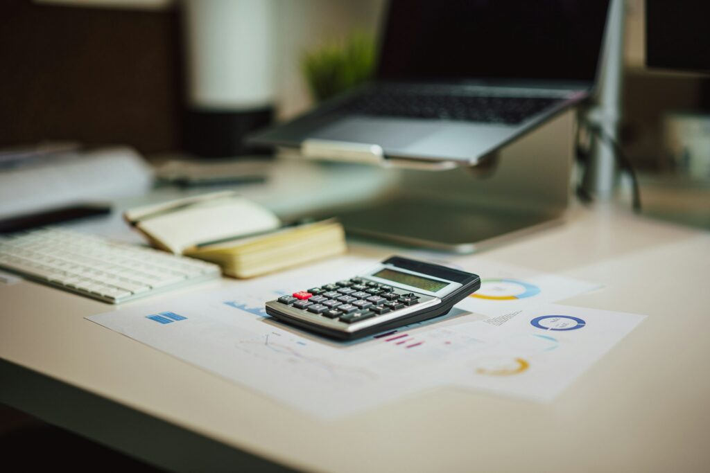 calculator, laptop, and documents on top of a desk