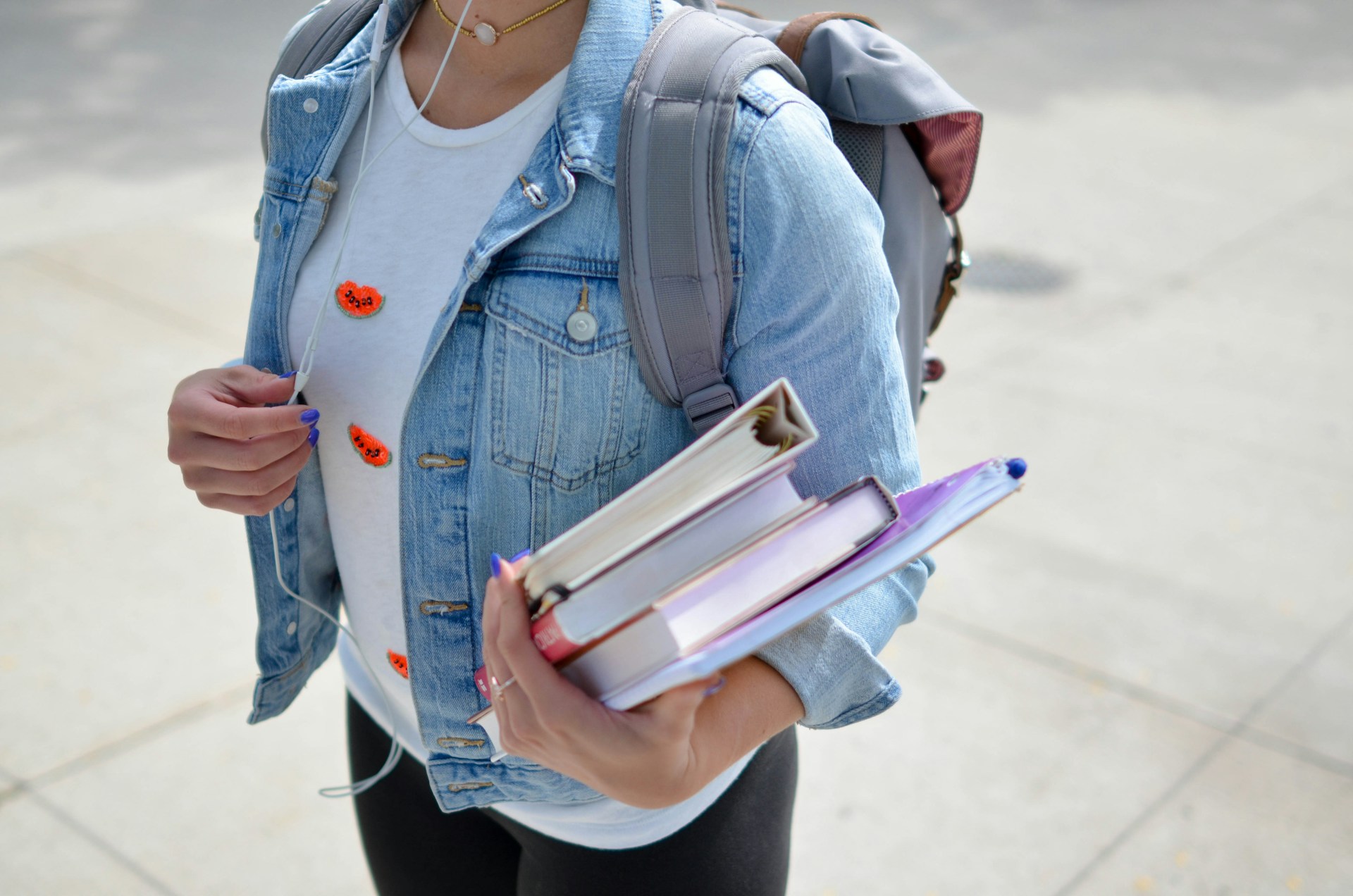 woman wearing blue denim jacket and holding books