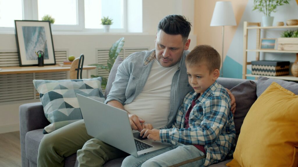 vitaly-gariev-JO4RmPyqkRY-unsplash father and son using laptop while seate don couch