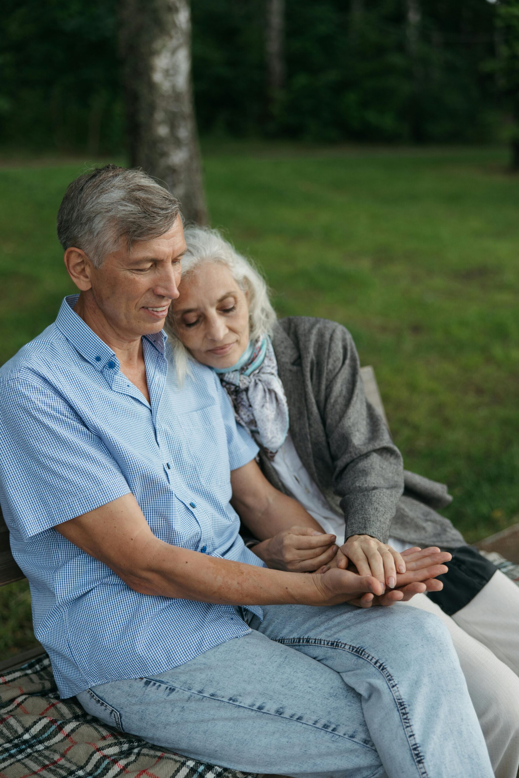 An elderly couple sitting on a bench in a park, sharing a tender moment of love and companionship.